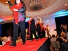 Bid assistants make their entrance down the runway in their red feather boas.